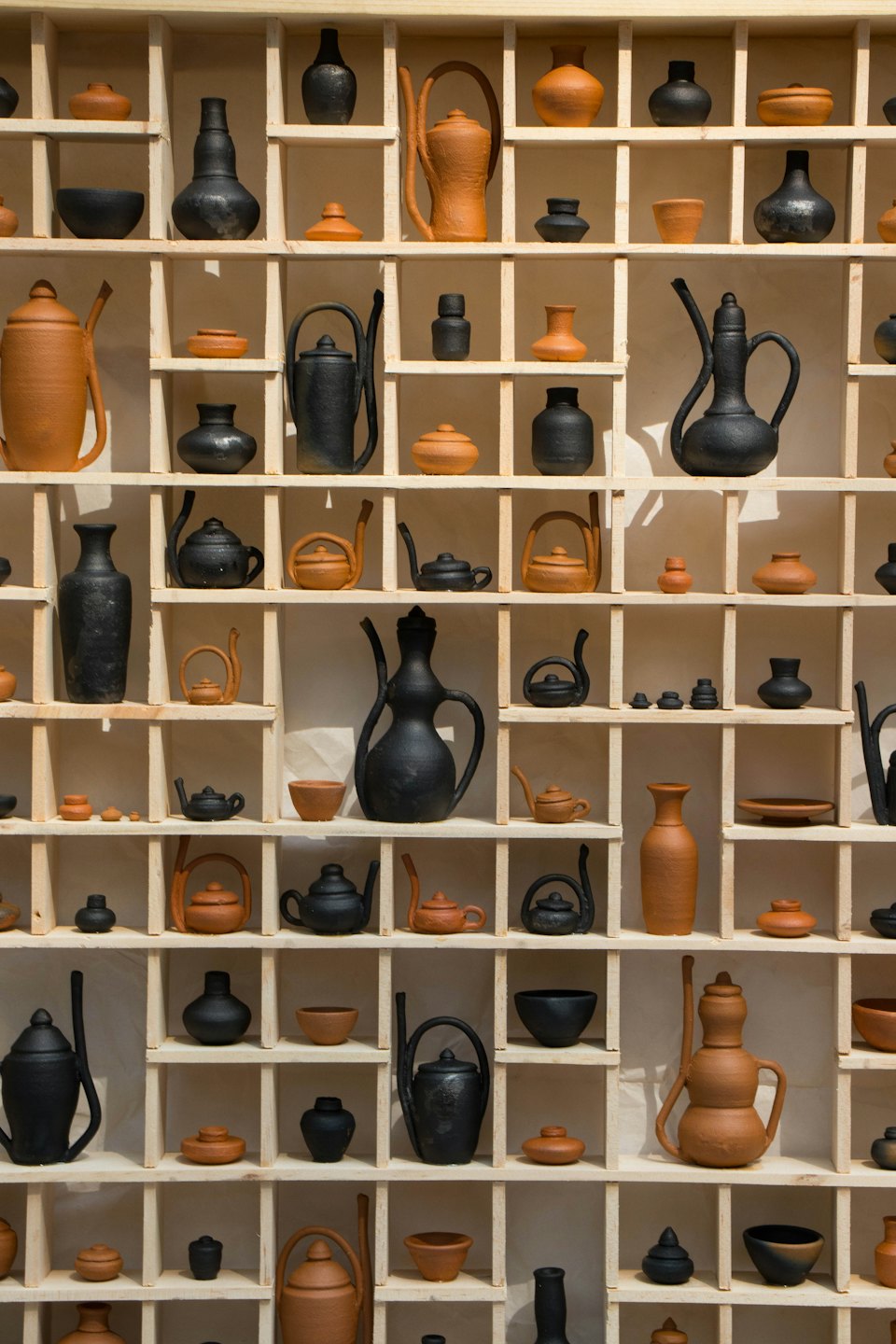 Handcrafted pottery displayed on a wooden shelf.