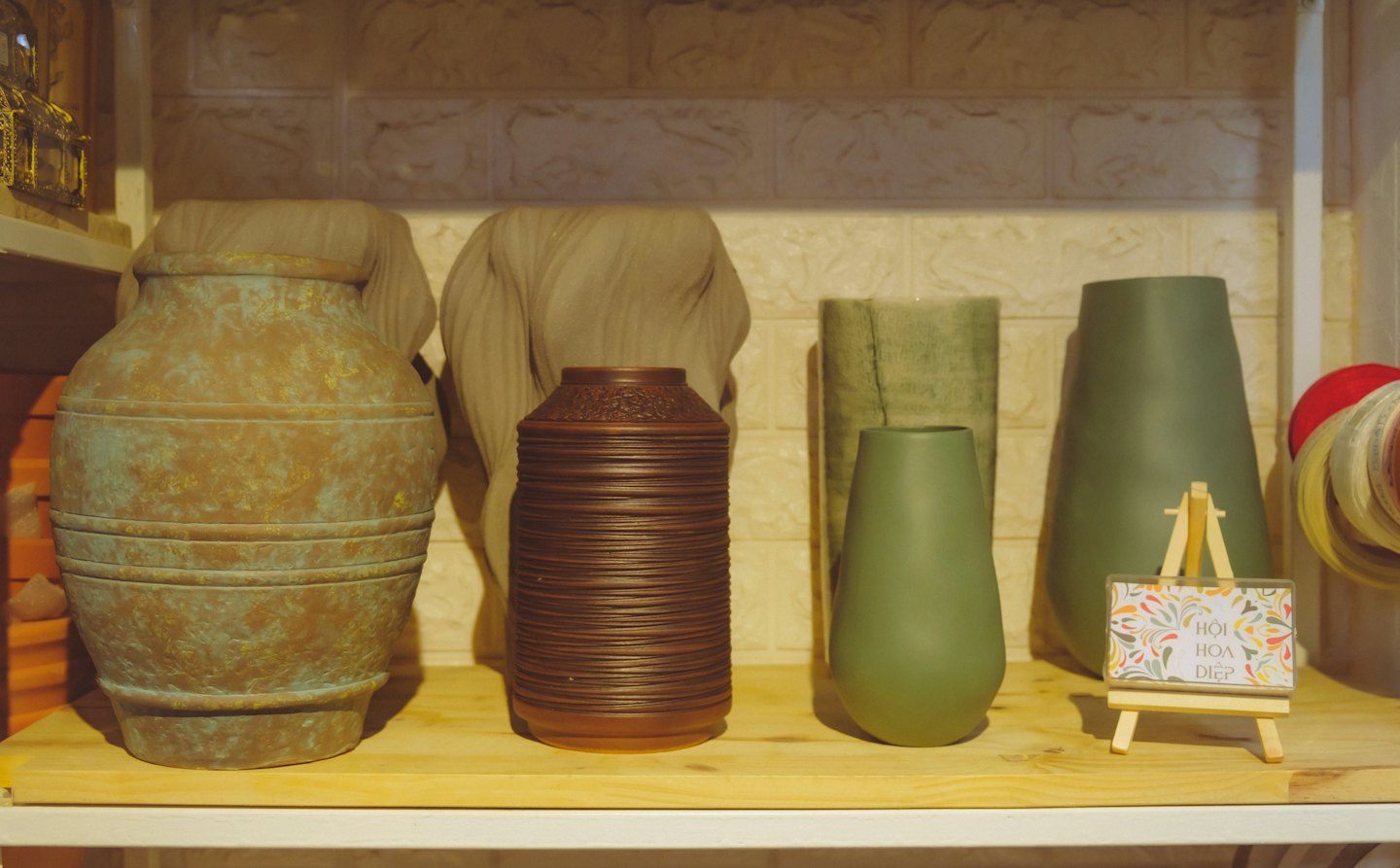 Handcrafted pottery and fabric sculptures arranged on a wooden shelf.