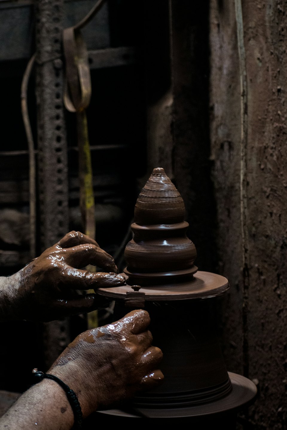 Potter shaping a wet clay vessel on a spinning wheel.